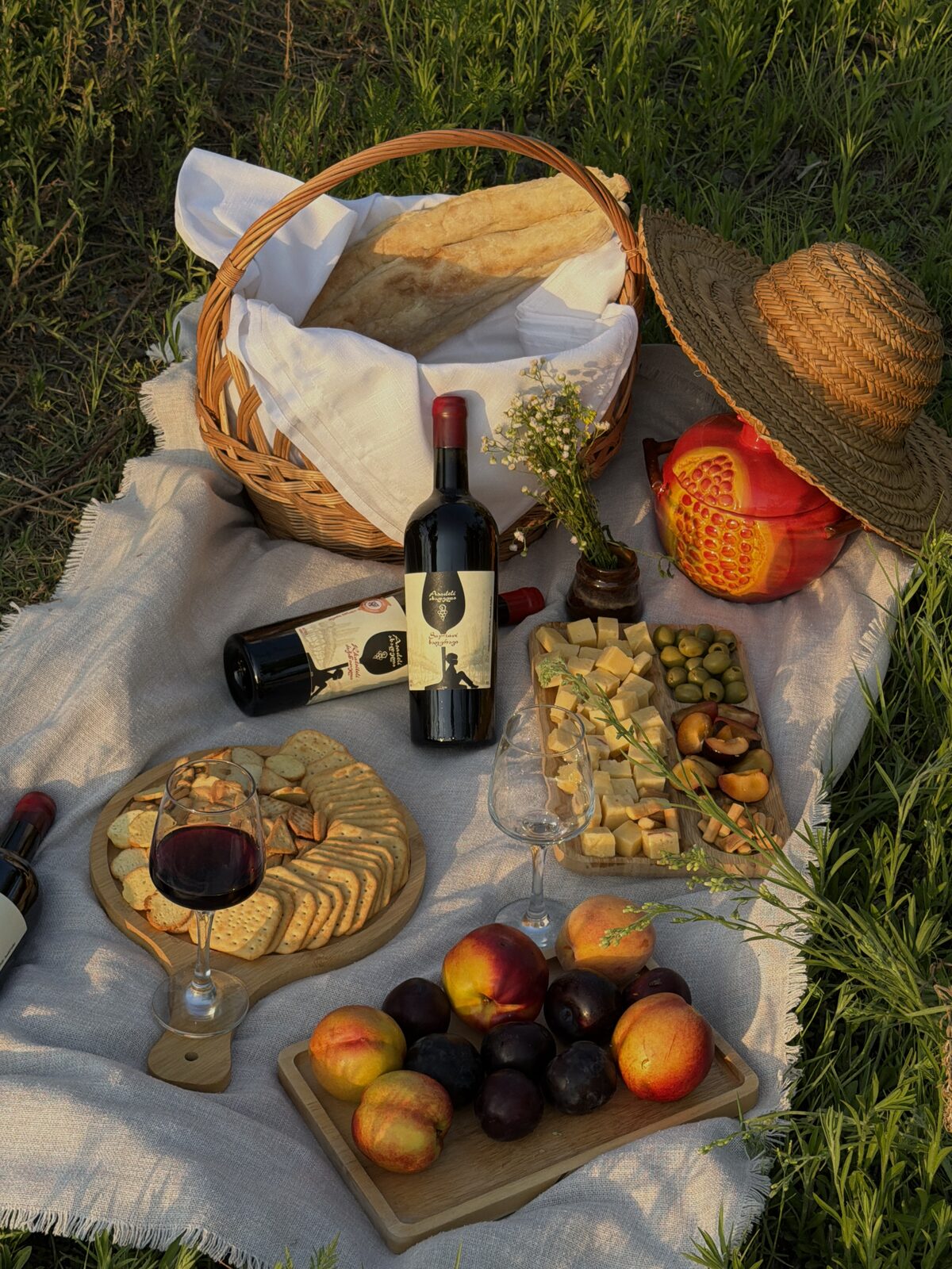 A table laid out on a cloth in the grass — bread, cheese, fruit and wine